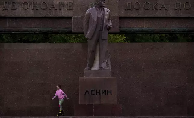 FILE - A girl skates next to a statue of Lenin, with the words "Board of Honor" written in Cyrillic in Romanian and Russian in Chisinau, Moldova, Friday, Nov. 1, 2024. (AP Photo/Vadim Ghirda, File)