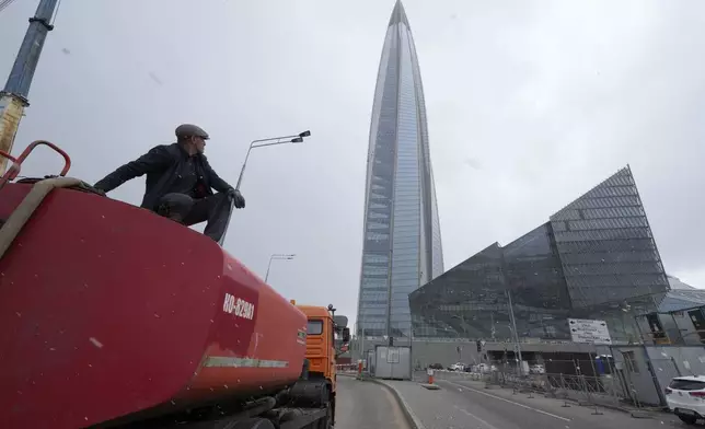 FILE - A worker sits on his water tank truck next to the business tower Lakhta Centre, the headquarters of Russian gas monopoly Gazprom in St. Petersburg, Russia, April 27, 2022. (AP Photo/Dmitri Lovetsky, File)