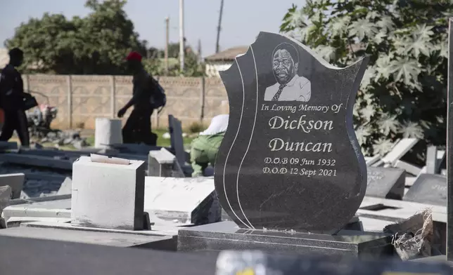 People walk past tombstones at a cemetory in Harare, Zimbabwe, Wednesday, Dec. 4, 2024. (AP Photo/Aaron Ufumeli)