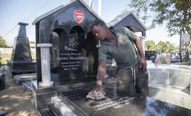 A worker cleans a tombstone at a cemetary in Harare, Zimbabwe, Wednesday, Dec. 4 2024. (AP Photo/Aaron Ufumeli)