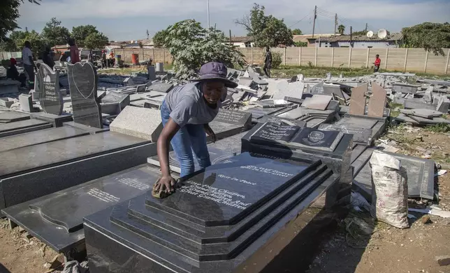 A worker cleans a tombstone at a cemetary in Harare, Zimbabwe, Wednesday, Dec. 4 2024. (AP Photo/Aaron Ufumeli)