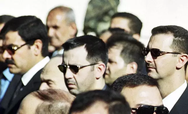 FILE - Bashar Assad, right, and his brother Maher Assad, center, stand during the funeral of their father, former President Hafez Assad, in Damascus, Syria, June 13, 2000. (AP Photo, File)