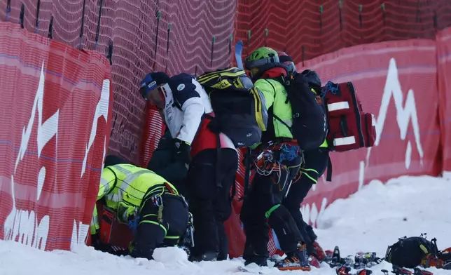 Medical staff are helping France's Cyprien Sarrazin after crashing during an alpine ski, men's World Cup downhill training, in Bormio, Italy, Friday, Dec. 27, 2024. (AP Photo/Alessandro Trovati)