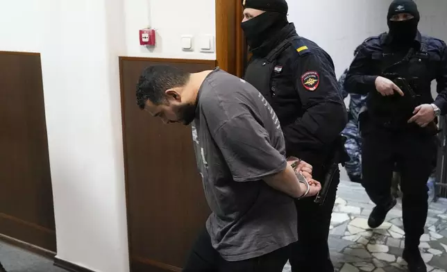 CORRECTS NAME TO AKHMADZHON KURBONOV - The man, whom Tass and RIA-Novosti news agencies identified as Akhmadzhon Kurbonov, suspected of involvement in the killing of Lt. Gen. Igor Kirillov, the head of Russia's Radiation, Biological and Chemical Defense Forces, and his assistant Ilya Polikarpov, is escorted to a courtroom at the Basmanny District Court in Moscow, Russia, Thursday, Dec. 19, 2024. (AP Photo/Pavel Bednyakov)