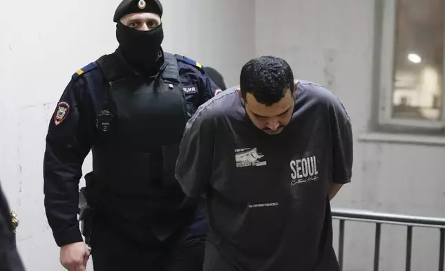 CORRECTS NAME TO AKHMADZHON KURBONOV - The man, whom Tass and RIA-Novosti news agencies identified as Akhmadzhon Kurbonov, suspected of involvement in the killing of Lt. Gen. Igor Kirillov, the head of Russia's Radiation, Biological and Chemical Defense Forces, and his assistant Ilya Polikarpov, is escorted to a courtroom at the Basmanny District Court in Moscow, Russia, Thursday, Dec. 19, 2024. (AP Photo/Pavel Bednyakov)