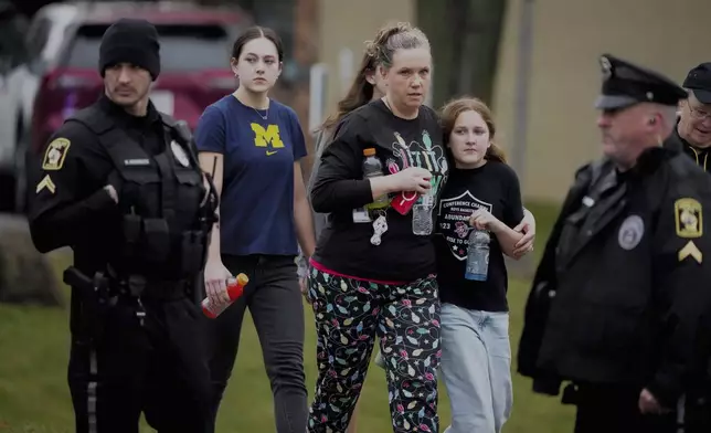 A family leave the shelter after multiple injuries were reported following a shooting at the Abundant Life Christian School, Monday, Dec. 16, 2024. (AP Photo/Morry Gash)