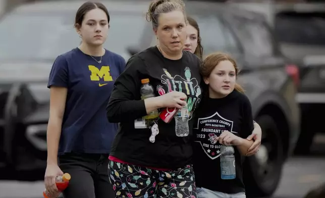 A family leave the shelter after multiple injuries were reported following a shooting at the Abundant Life Christian School, Monday, Dec. 16, 2024. (AP Photo/Morry Gash)