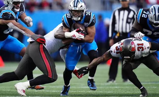 Carolina Panthers running back Chuba Hubbard is tackled by Tampa Bay Buccaneers linebacker SirVocea Dennis during the first half of an NFL football game, Sunday, Dec. 1, 2024, in Charlotte, N.C. (AP Photo/Rusty Jones)