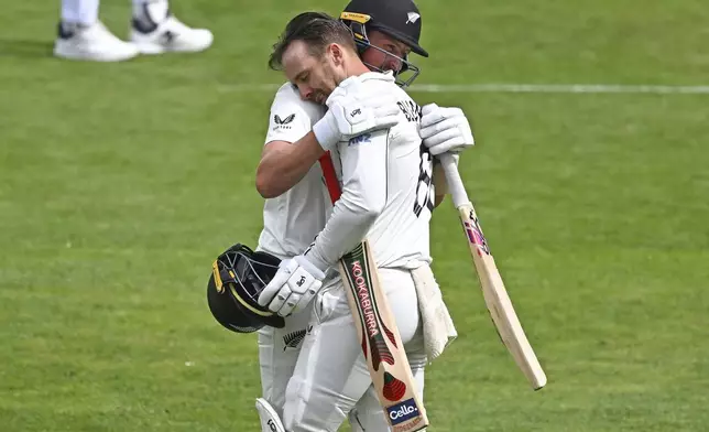 New Zealand's Nathan Smith, right, embraces teammate Tom Blundell after he scored a century during play on day three of the second cricket test between New Zealand and England at the Basin Reserve in Wellington, New Zealand, Sunday, Dec.8, 2024. (Kerry Marshall/Photosport via AP)