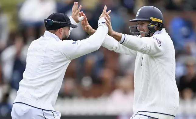 England's Ben Duckett, left, celebrates with teammate Joe Root after taking a catch to dismiss New Zealand's Tom Blundell during play on day three of the second cricket test between New Zealand and England at the Basin Reserve in Wellington, New Zealand, Sunday, Dec.8, 2024. (Andrew Cornaga/Photosport via AP)