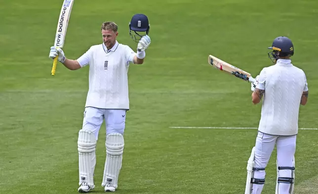 England's Joe Root celebrates after scoring a century as teammate Ben Stokes, right, watches during play on day three of the second cricket test between New Zealand and England at the Basin Reserve in Wellington, New Zealand, Sunday, Dec.8, 2024.(Kerry Marshall/Photosport via AP)