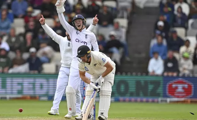 New Zealand's Glenn Phillips reacts after he was out bowled as England's Ollie Pope celebrates during play on day three of the second cricket test between New Zealand and England at the Basin Reserve in Wellington, New Zealand, Sunday, Dec.8, 2024. (Kerry Marshall/Photosport via AP)