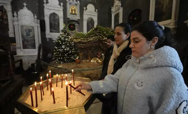 A Syrian Christians woman lights a candle during the first Sunday Mass since Syrian President Bashar Assad's ouster, at Mariamiya Orthodox Church in old Damascus, Syria, Sunday, Dec. 15, 2024. (AP Photo/Hussein Malla)