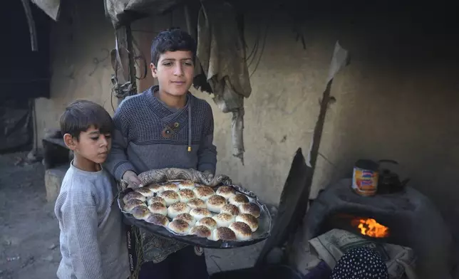 A Palestinian boy carries a tray of baked goods from a clay oven amid dire food shortages in Deir al-Balah, Gaza Strip, Monday, Dec. 2, 2024. (AP Photo/Abdel Kareem Hana)