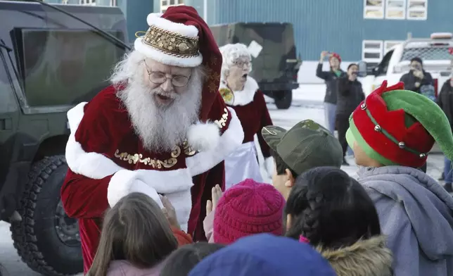 Santa Claus meets children after arriving at the school in Yakutat, Alaska, as part of the Alaska National Guard's Operation Santa initiative that brings Christmas to an Indigenous community that has suffered a hardship, Wednesday, Dec. 18, 2024. (AP Photo/Mark Thiessen).