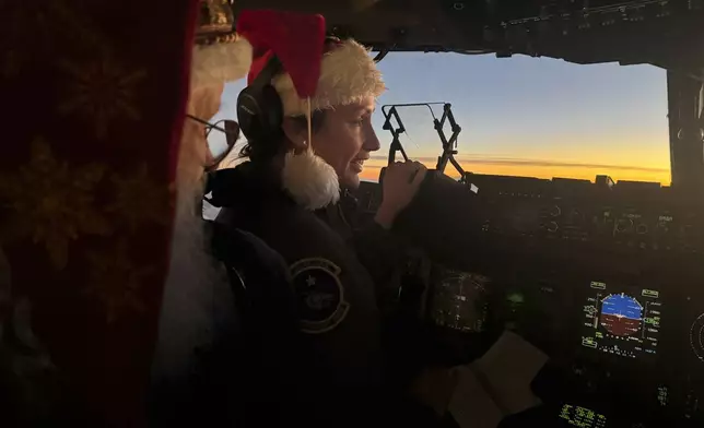 Santa Claus speaks to pilot Maj. Lauren Schumacher en route to Yakutat, Alaska, as part of the Alaska National Guard's Operation Santa initiative that brings Christmas to an Indigenous community that has suffered a hardship, Wednesday, Dec. 18, 2024,. (AP Photo/Mark Thiessen)