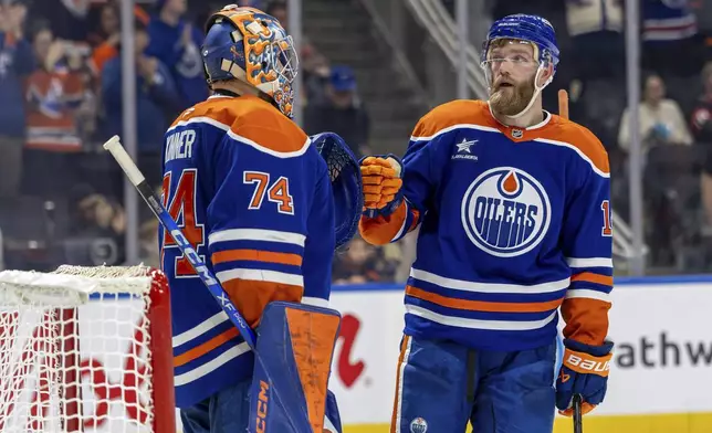 Edmonton Oilers' Stuart Skinner (74) and Mattias Ekholm, right, celebrate after their win over the Ottawa Senators in an NHL hockey game action in Edmonton, Alberta, Sunday, Dec. 22, 2024. (Timothy Matwey/The Canadian Press via AP)