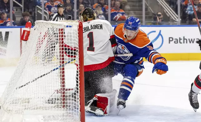 Edmonton Oilers' Vasily Podkolzin (92) drives the net and crashes into Ottawa Senators goaltender Leevi Merilainen (1) during second-period NHL hockey game action in Edmonton, Alberta, Sunday, Dec. 22, 2024. (Timothy Matwey/The Canadian Press via AP)