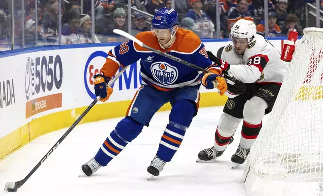 Edmonton Oilers' Corey Perry (90) battles for the puck against Ottawa Senators' Zack Ostapchuk (38) during second-period NHL hockey game action in Edmonton, Alberta, Sunday, Dec. 22, 2024. (Timothy Matwey/The Canadian Press via AP)