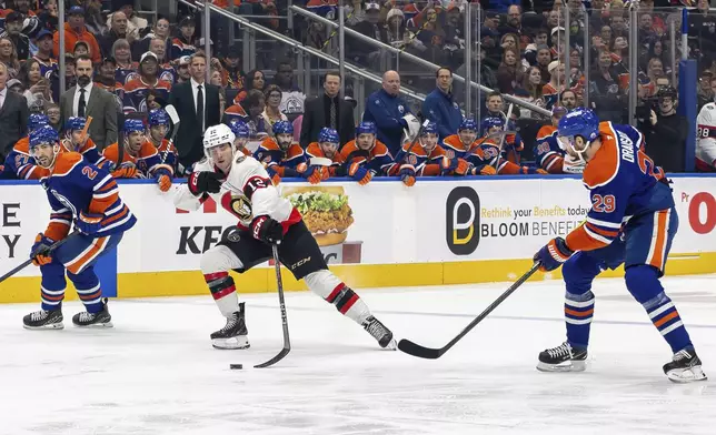 Ottawa Senators' Shane Pinto (12) battles for the puck against Edmonton Oilers' Leon Draisaitl (29) during first-period NHL hockey game action in Edmonton, Alberta, Sunday, Dec. 22, 2024. (Timothy Matwey/The Canadian Press via AP)