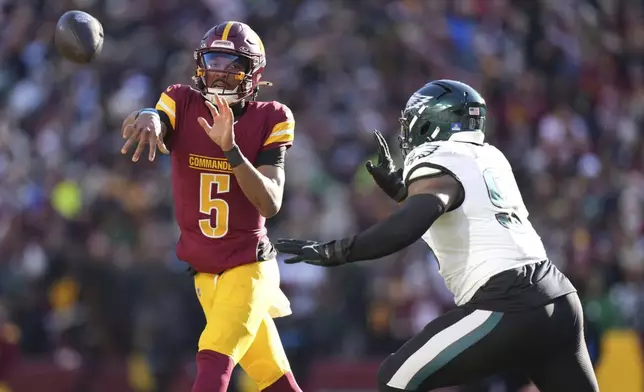 Washington Commanders quarterback Jayden Daniels (5) throwing the ball as Philadelphia Eagles defensive tackle Jalen Carter (98) charges in during the first half of an NFL football game, Sunday, Dec. 22, 2024, in Landover, Md. (AP Photo/Stephanie Scarbrough)