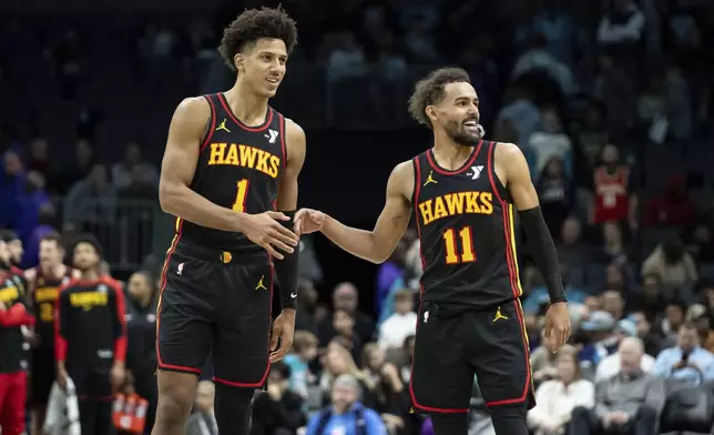 Atlanta Hawks forward Jalen Johnson (1) and guard Trae Young (11) high-five during the second half of an NBA basketball game against the Charlotte Hornets, Saturday, Nov. 30, 2024, in Charlotte, N.C. (AP Photo/Matt Kelley)