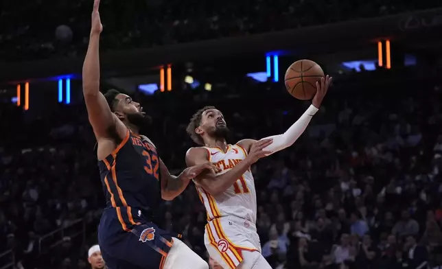 Atlanta Hawks' Trae Young (11) drives past New York Knicks' Karl-Anthony Towns (32) during an Emirates Cup NBA basketball game Wednesday, Dec. 11, 2024, in New York. (AP Photo/Frank Franklin II)