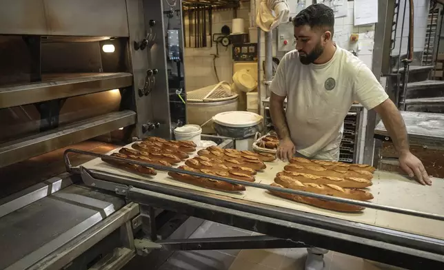 An employee removes bread for the oven in a bakery in Paris, Monday, Dec. 16, 2024 as butter has shot up in price across Europe in recent months, adding more pain to consumers this holiday season after years of inflation in the wake of the COVID-19 pandemic and war in Ukraine.(AP Photo/Aurelien Morissard)