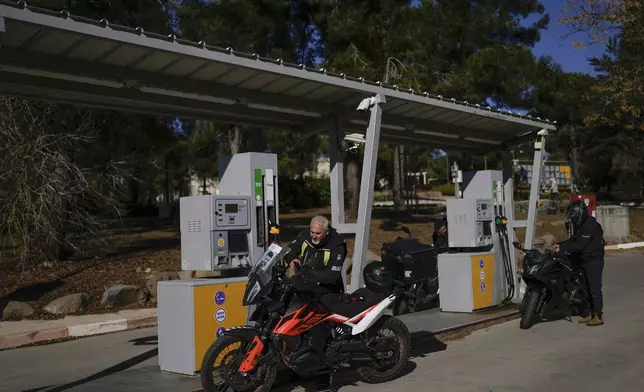 A man waits to fuel up his motorbike in the kibbutz of Ein Zivan in the Israeli-annexed Golan Heights, which most of the world considers occupied Syrian territory, Thursday, Dec. 19, 2024. (AP Photo/Matias Delacroix)