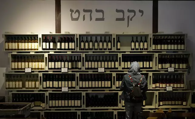 A woman looks at wine bottles in the Bahat winery in the kibbutz of Ein Zivan in the Israeli-annexed Golan Heights, which most of the world considers occupied Syrian territory, Thursday, Dec. 19, 2024. (AP Photo/Matias Delacroix)