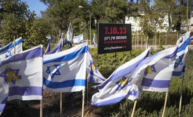 Israeli flags fly next to a sign in Hebrew that reads, "The families of Ein Zivan with the families of the hostages," in the kibbutz of Ein Zivan in the Israeli-annexed Golan Heights, which most of the world considers occupied Syrian territory, Thursday, Dec. 19, 2024. (AP Photo/Matias Delacroix)