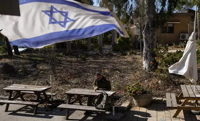 An Israeli soldier sits at a table inside the Bahat winery in the kibbutz of Ein Zivan in the Israeli-annexed Golan Heights, which most of the world considers occupied Syrian territory, Thursday, Dec. 19, 2024. (AP Photo/Matias Delacroix)