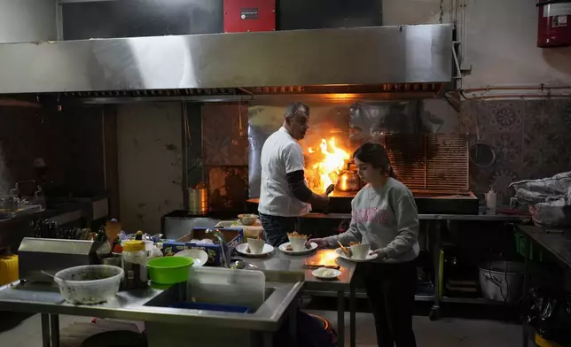 Khaled Elshaer cooks at his restaurant in Masada in the Israeli-annexed Golan Heights, which most of the world considers occupied Syrian territory, Thursday, Dec. 19, 2024. (AP Photo/Matias Delacroix)