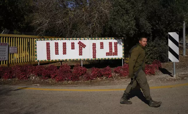 An Israeli soldier walks past a sign that reads "Ein Zivan" at the entrance to the kibbutz of the same name in the Israeli-annexed Golan Heights, which most of the world considers occupied Syrian territory, Thursday, Dec. 19, 2024. (AP Photo/Matias Delacroix)