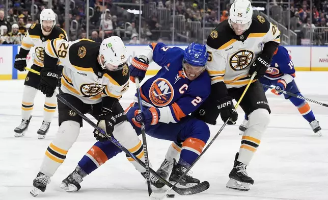 New York Islanders left wing Anders Lee (27), center, fight for the puck with Boston Bruins defensemen Parker Wotherspoon (29), left, and Brandon Carlo (25), right during the second period of an NHL hockey game, Wednesday, Nov. 27, 2024, in Elmont, N.Y. (AP Photo/Julia Demaree Nikhinson)