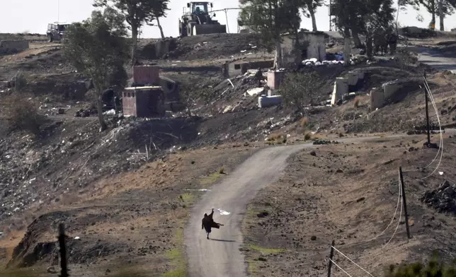 A Syrian man waves a white flag, as he approaches Israeli soldiers to negotiate with them, where they set their new position at an abandoned Syrian military base, in Maariyah village near the border with Israel in southern Syria, Thursday, Dec. 19, 2024. (AP Photo/Hussein Malla)