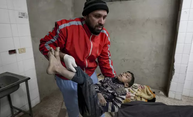 EDS NOTE: GRAPHIC CONTENT - A Palestinian medic holds the body of a child killed in the Israeli bombardment of the Gaza Strip in the morgue at Al-Aqsa Hospital in Deir al-Balah, Thursday, Dec. 19, 2024. (AP Photo/Abdel Kareem Hana)