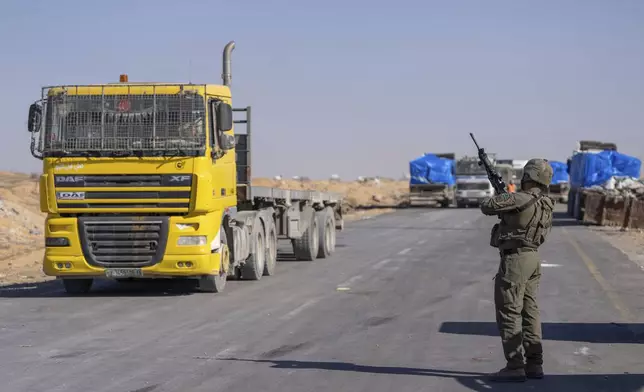 An Israeli soldier stands guard on the Palestinian side of the Kerem Shalom aid crossing as reporters tour the area in the Gaza Strip, Thursday, Dec. 19, 2024. (AP Photo/Ohad Zwigenberg)