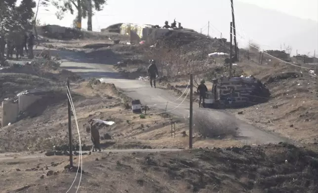 A Syrian man, left, waves a white flag as he approaches Israeli soldiers to negotiate with them, where they set their new position at an abandoned Syrian military base, in Maaryeh village near the border with Israel, in southern Syria, Thursday, Dec. 19, 2024. (AP Photo/Hussein Malla)