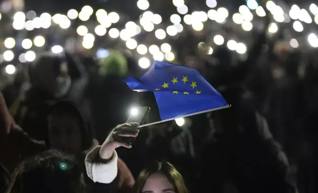A demonstrator holds the EU flag during a rally outside the parliament's building to protests against the government's decision to suspend negotiations on joining the European Union, in Tbilisi, Georgia, Wednesday, Dec. 4, 2024. (AP Photo/Pavel Bednyakov)