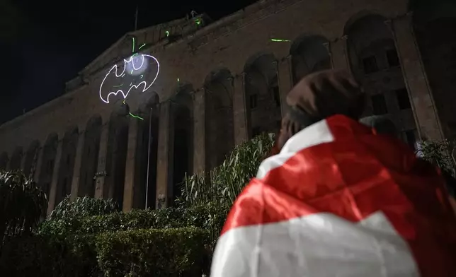 Demonstrators draw a bat with a laser on the facade of the parliament building during a rally to protests against the government's decision to suspend negotiations on joining the European Union, in Tbilisi, Georgia, Wednesday, Dec. 4, 2024. (AP Photo/Pavel Bednyakov)