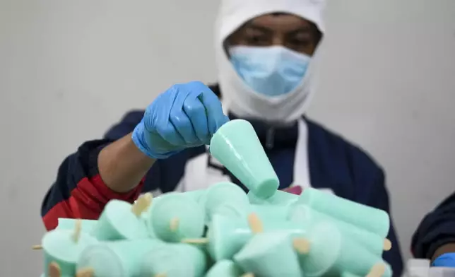 A worker packages popsicles at an artisanal factory in Salcedo, Ecuador, Thursday, Nov. 28, 2024, amid a wave of power outages, triggered by a prolonged dry spell. (AP Photo/Dolores Ochoa)