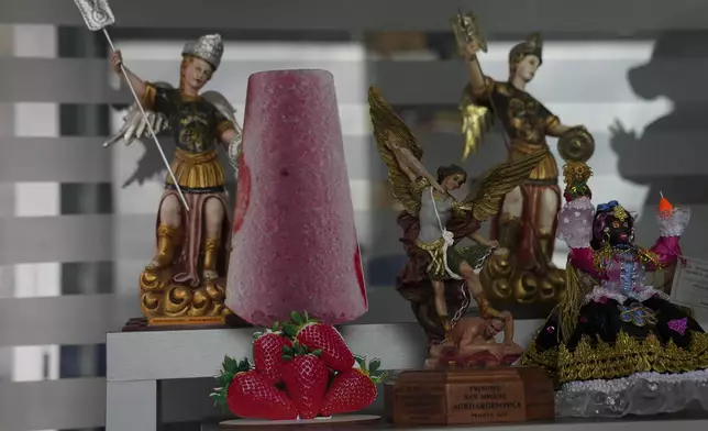 A cutout of a popsicle adorns a shelf next to a statue of patron saint Michael the Archangel in Salcedo, Ecuador, Thursday, Nov. 28, 2024, amid a wave of power outages, triggered by a prolonged dry spell. (AP Photo/Dolores Ochoa)