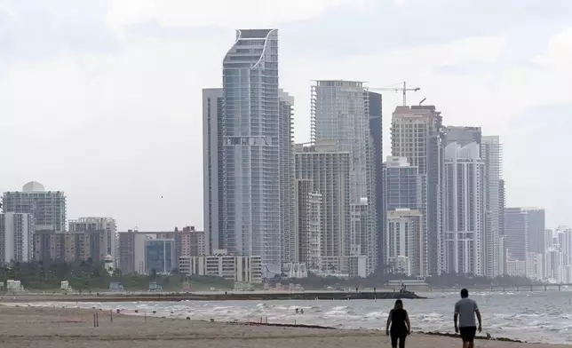 FILE - A couple walk on the beach in Surfside, Fla., Tuesday, June 29, 2021. (AP Photo/Marta Lavandier, File)