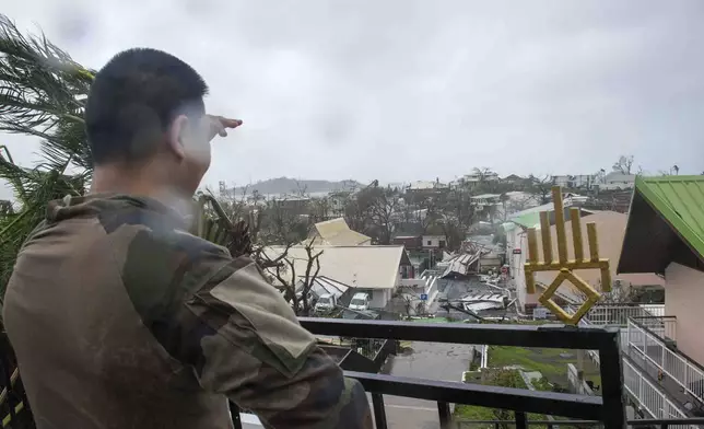 This photo provided Sunday Dec.15, 2024 by the French Army shows a soldier looking at damages in the French territory of Mayotte in the Indian Ocean, after Cyclone Chido caused extensive damage with reports of several fatalities. (Etat Major des Armées via AP)