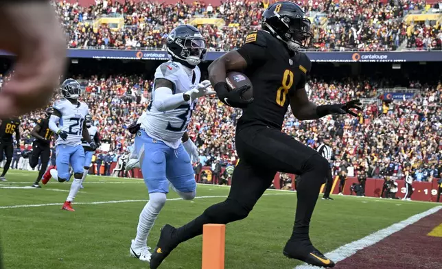 Washington Commanders running back Brian Robinson Jr. (8) runs for a touchdown past Tennessee Titans cornerback Daryl Worley, left, during the first half of an NFL football game Sunday, Dec. 1, 2024, in Landover, Md. (AP Photo/Steve Ruark)