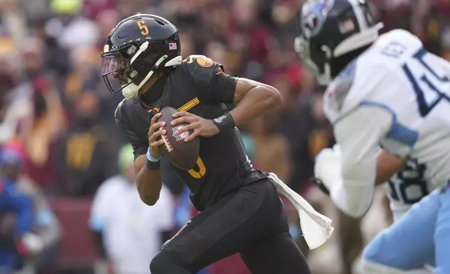 Washington Commanders quarterback Jayden Daniels (5) runs the ball past Tennessee Titans defenders during the first half of an NFL football game Sunday, Dec. 1, 2024, in Landover, Md. (AP Photo/Matt Slocum)