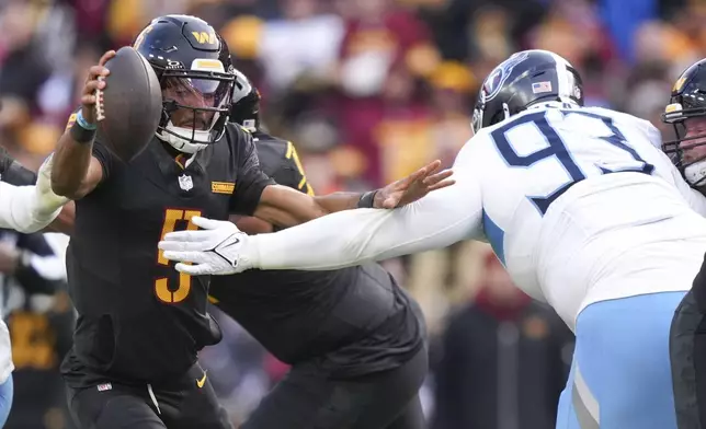 Washington Commanders quarterback Jayden Daniels (5) is tackled by Tennessee Titans defensive tackle T'Vondre Sweat (93) during the first half of an NFL football game Sunday, Dec. 1, 2024, in Landover, Md. (AP Photo/Matt Slocum)