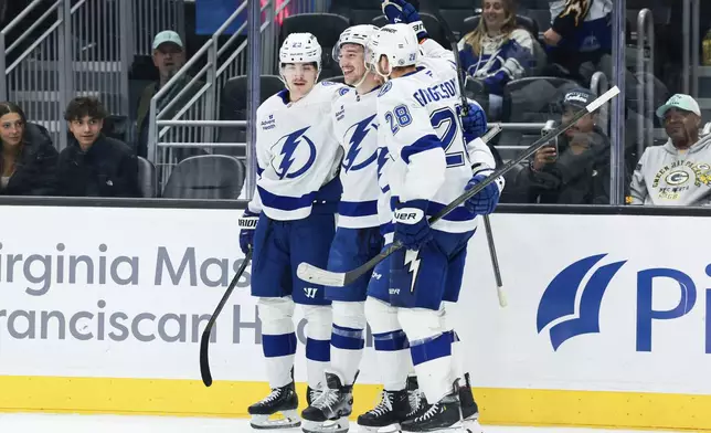 Tampa Bay Lightning defenseman Declan Carlile, center, celebrates with teammates Michael Eyssimont, left, and Zemgus Girgensons, right, after scoring a goal during the third period of an NHL hockey game against the Seattle Kraken Saturday, Dec. 14, 2024, in Seattle. (AP Photo/Maddy Grassy)