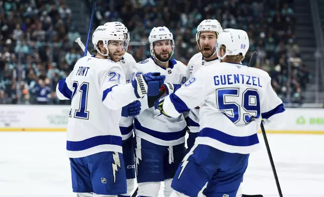 Tampa Bay Lightning players celebrate after a goal by center Brayden Point during the first period ofan NHL hockey game against the Seattle Kraken Saturday, Dec. 14, 2024, in Seattle. (AP Photo/Maddy Grassy)